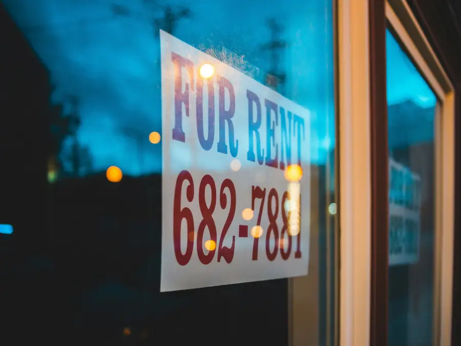 a white sign with black text that reads for rent is displayed in a well-lit window at night. The phone number "682-78811" is also visible on the sign.